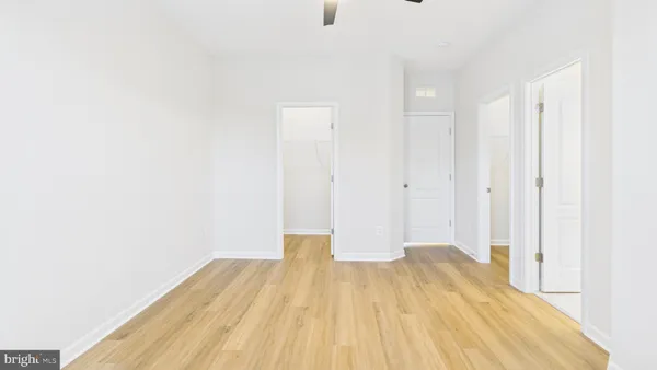 an empty room with wooden floor cabinet and windows