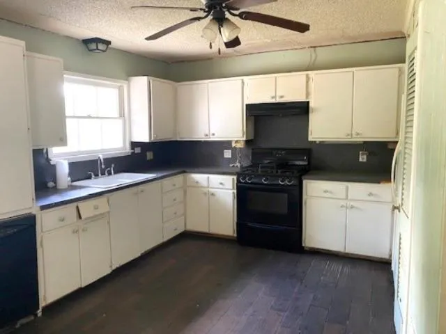 a kitchen with a sink white cabinets and white appliances