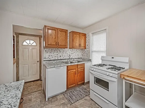 a kitchen with granite countertop a stove sink and cabinets
