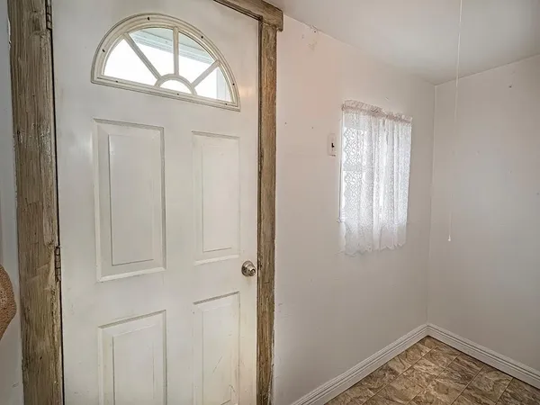 an empty room with wooden floor closet and windows