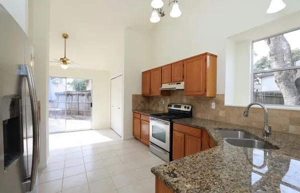 a kitchen with stainless steel appliances granite countertop a stove a sink a refrigerator a counter space and cabinets