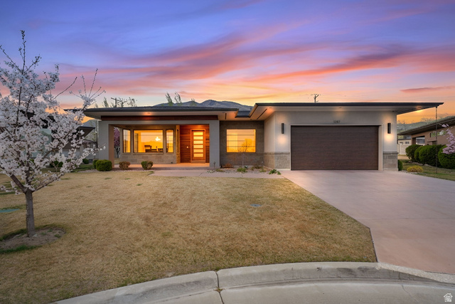 Prairie-style house with an attached garage, concrete driveway, a yard, and stucco siding