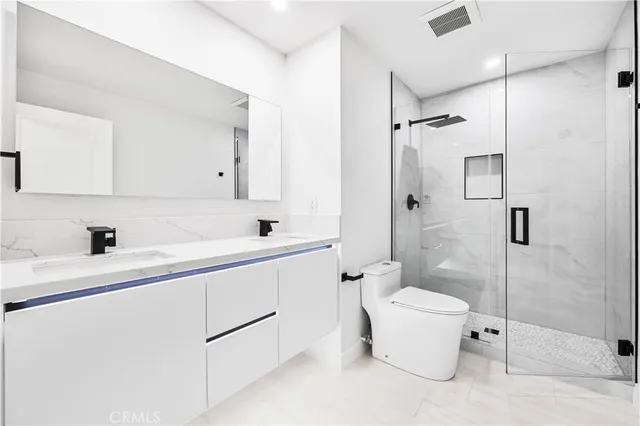 a bathroom with a granite countertop sink a toilet and shower