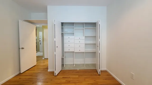 a view of empty room with wooden floor and brick walls