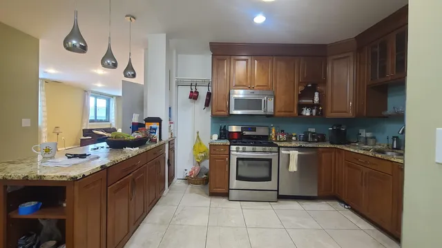 a kitchen with stainless steel appliances granite countertop a stove a sink and a refrigerator