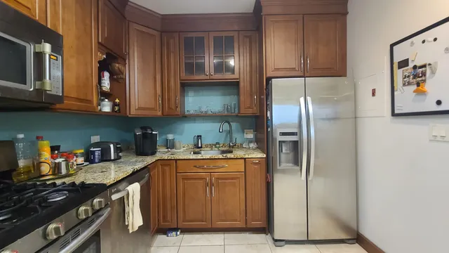 a kitchen with stainless steel appliances granite countertop a refrigerator and a stove top oven