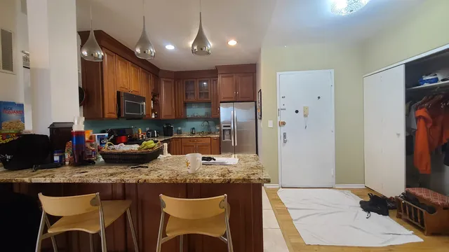 a kitchen with kitchen island granite countertop a sink cabinets and refrigerator