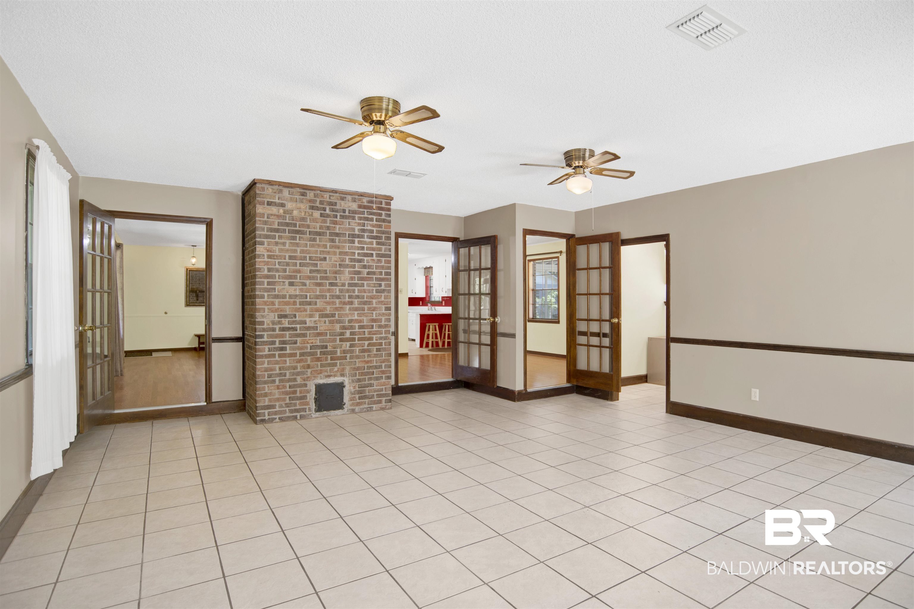 30888 Cemetery Road Daphne, AL 36527 - Photo 14 of 36 Spacious room featuring light-toned tile flooring, a prominent brick fireplace, and dual ceiling fans with integrated lighting