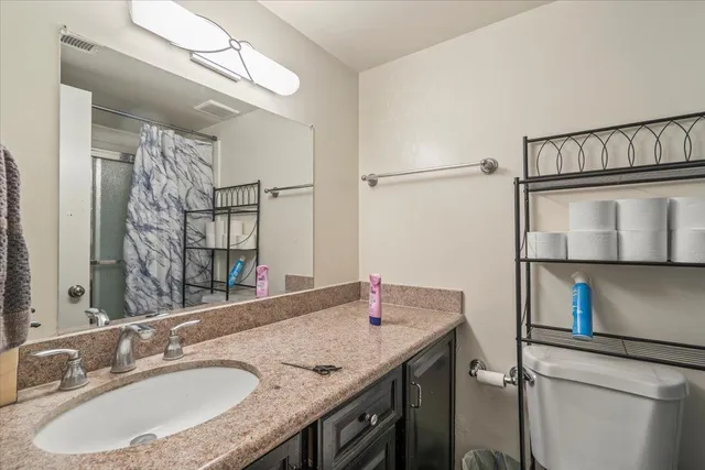 a bathroom with a granite countertop sink a mirror and shower