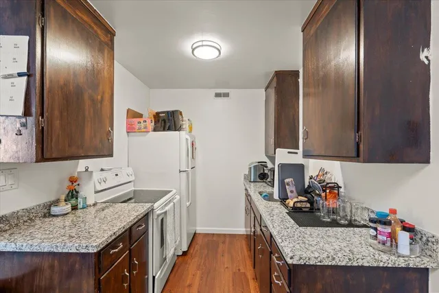 a kitchen with granite countertop a sink stove and refrigerator