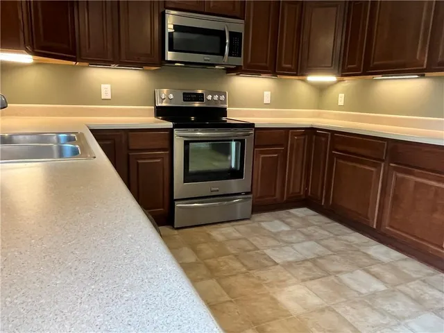 a kitchen with granite countertop a stove top oven microwave and cabinets