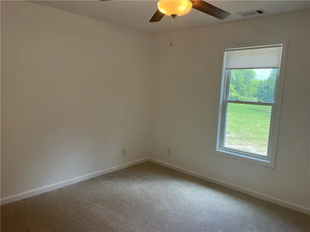 an empty room with a window and chandelier fan