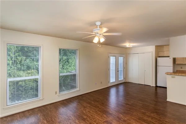 a view of an empty room with wooden floor and a window