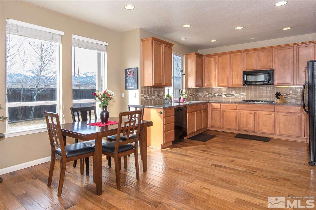 400 Parade Drive Reno, NV 89521 - Photo 6 of 24 a kitchen with stainless steel appliances granite countertop wooden floor a dining table and chairs