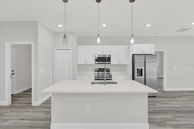 a kitchen with kitchen island white cabinets and stainless steel appliances
