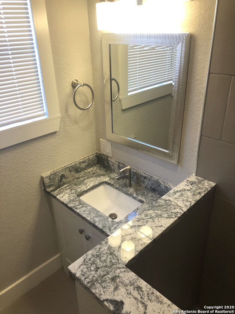 603 Devine Street, Unit 2 San Antonio, TX 78210 - Photo 11 of 16 a bathroom with a granite countertop sink and a mirror