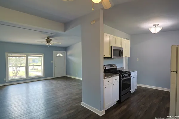 a view of a kitchen with a stove wooden floor cabinet and a living room