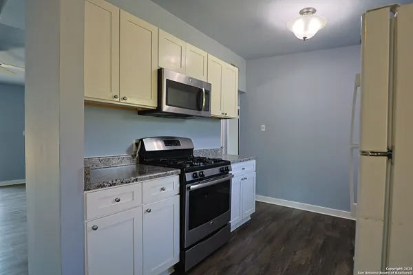 a kitchen with stainless steel appliances granite countertop a stove a microwave and a white cabinets