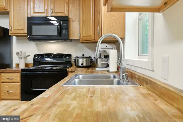 a kitchen with stainless steel appliances a refrigerator a stove a sink and a view of living room