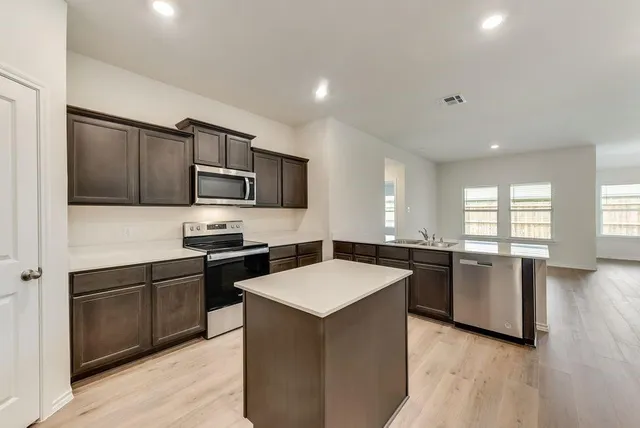 a kitchen with a refrigerator stove top oven and sink