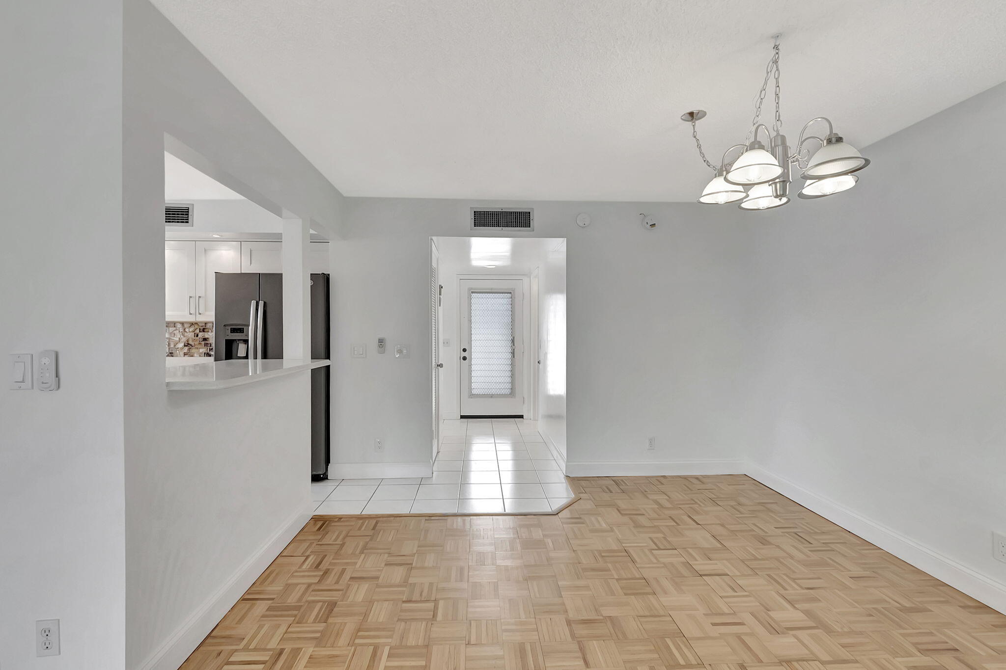 124 Capri B Delray Beach, FL 33484 - Photo 7 of 69 a view of a hallway with wooden floor and a chandelier