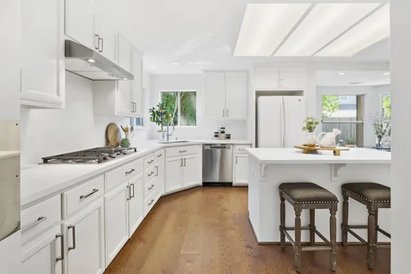a kitchen with white cabinets and chairs