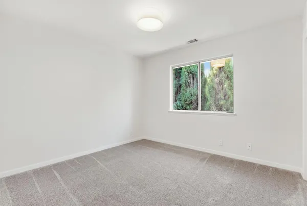 an empty room with a window and a ceiling fan