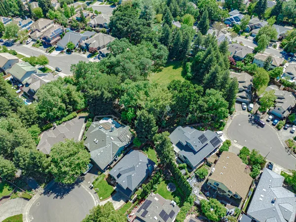 an aerial view of residential houses with outdoor space and trees all around