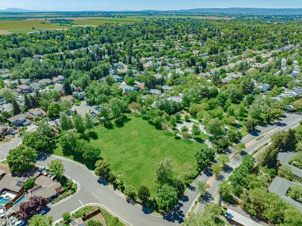 an aerial view of residential houses with outdoor space and trees