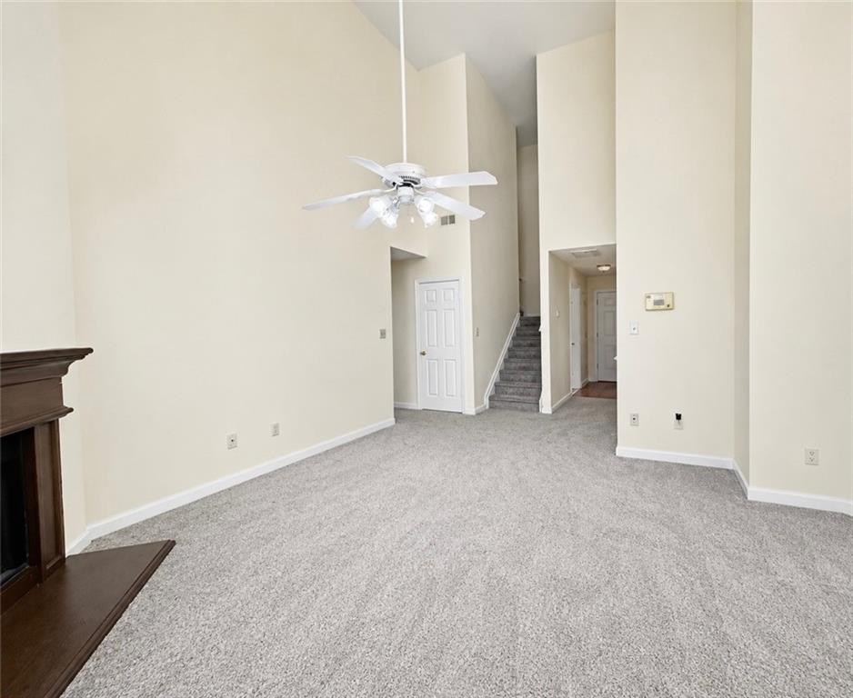 6936 Red Bone Way Stonecrest, GA 30038 - Photo 7 of 17 an empty room with a fireplace and a chandelier fan