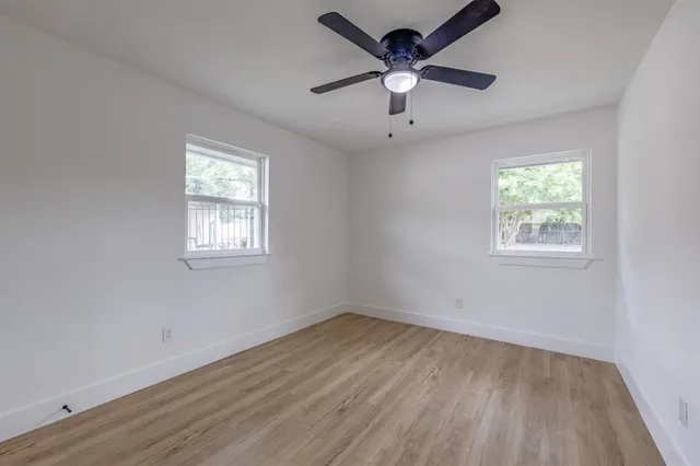 a view of empty room with wooden floor and fan