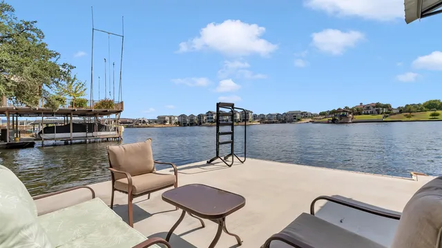 a view of a patio with table and chairs under an umbrella with wooden floor and fence