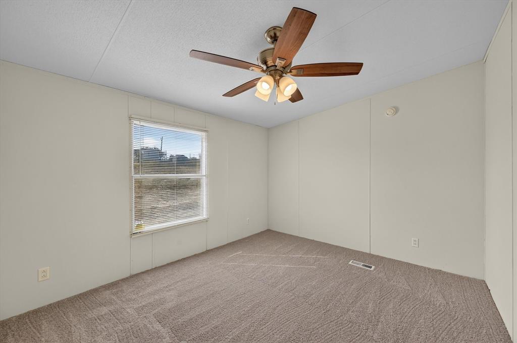 246 PR-4443 Rhome, TX 76078 - Photo 21 of 35 Neutral tone wall paneling with a window, ceiling fan with integrated lighting, and carpeted flooring