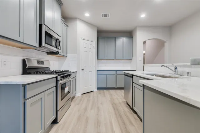 a kitchen with stainless steel appliances granite countertop a sink stove and refrigerator