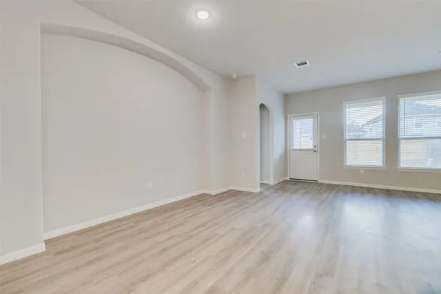 an empty room with wooden floor and windows