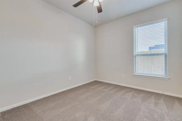 an empty room with a window and a ceiling fan