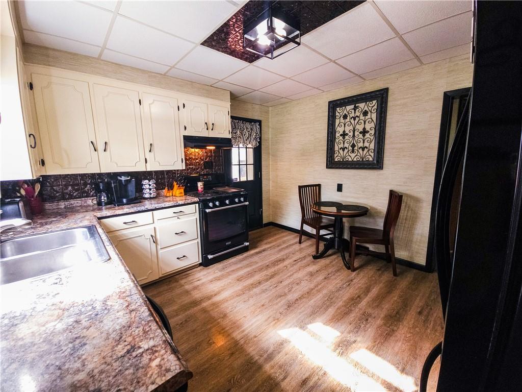 496 Great Belt Road Butler, PA 16002 - Photo 3 of 33 a kitchen with stainless steel appliances kitchen island granite countertop a stove a sink a dining table and chairs with wooden floor