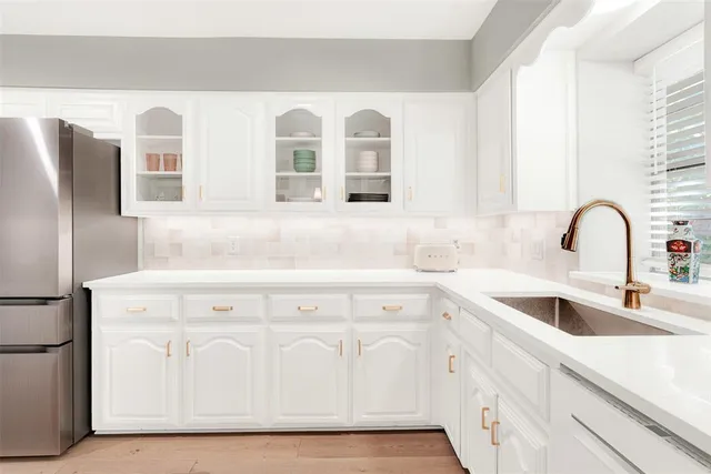 a kitchen with white cabinets and sink