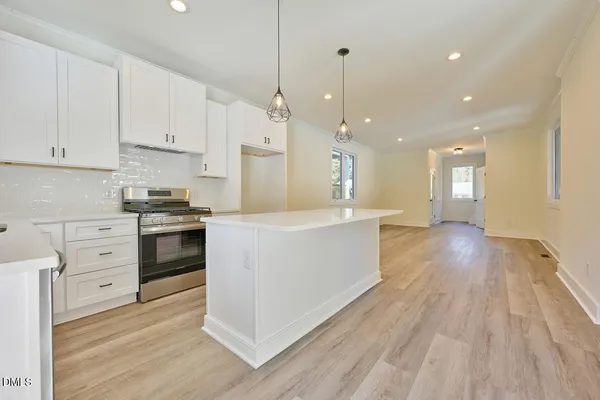 a large kitchen with stainless steel appliances granite countertop a large center island attached withe living room