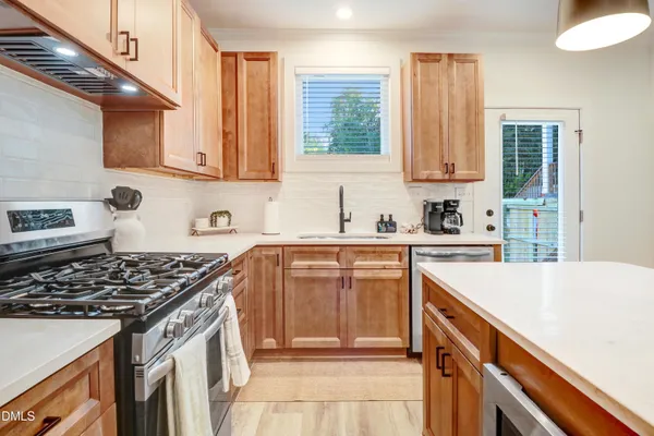 a kitchen with stainless steel appliances kitchen island granite countertop a sink a stove a refrigerator and island with wooden floor