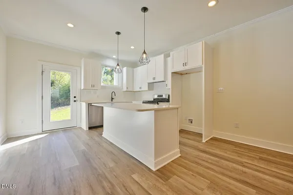 a kitchen with stainless steel appliances granite countertop a refrigerator a sink dishwasher a stove and white countertops with wooden floor