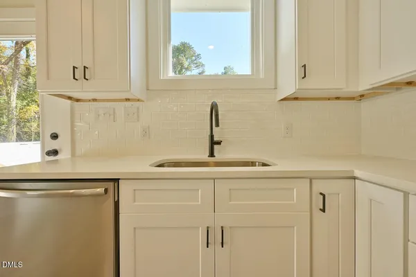 a kitchen with stainless steel appliances white cabinets and a window