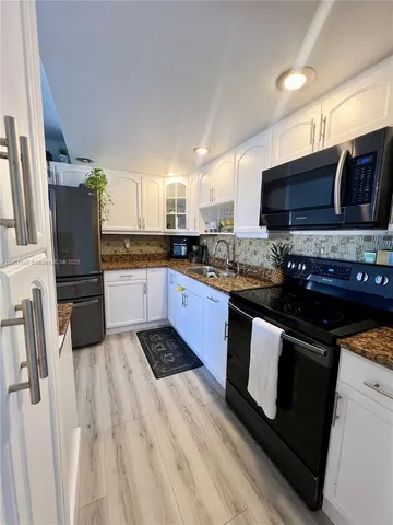 a kitchen with stainless steel appliances granite countertop a stove a sink dishwasher a microwave oven and a refrigerator