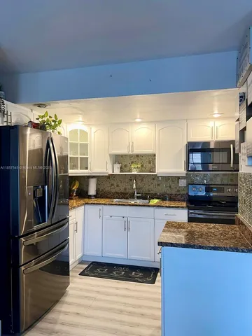 a kitchen with granite countertop a refrigerator and a stove top oven