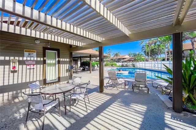 a view of a patio with table and chairs potted plants and floor to ceiling window