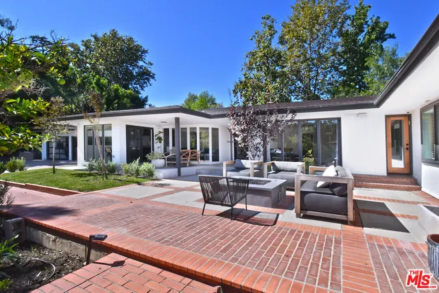 a view of a patio with couches and table and chairs with wooden floor and fence