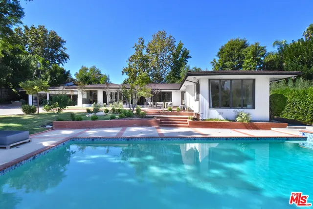 a view of a patio with couches a table and chairs with wooden floor and fence