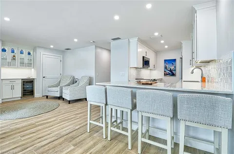 a kitchen with stainless steel appliances granite countertop a table chairs sink refrigerator and cabinets