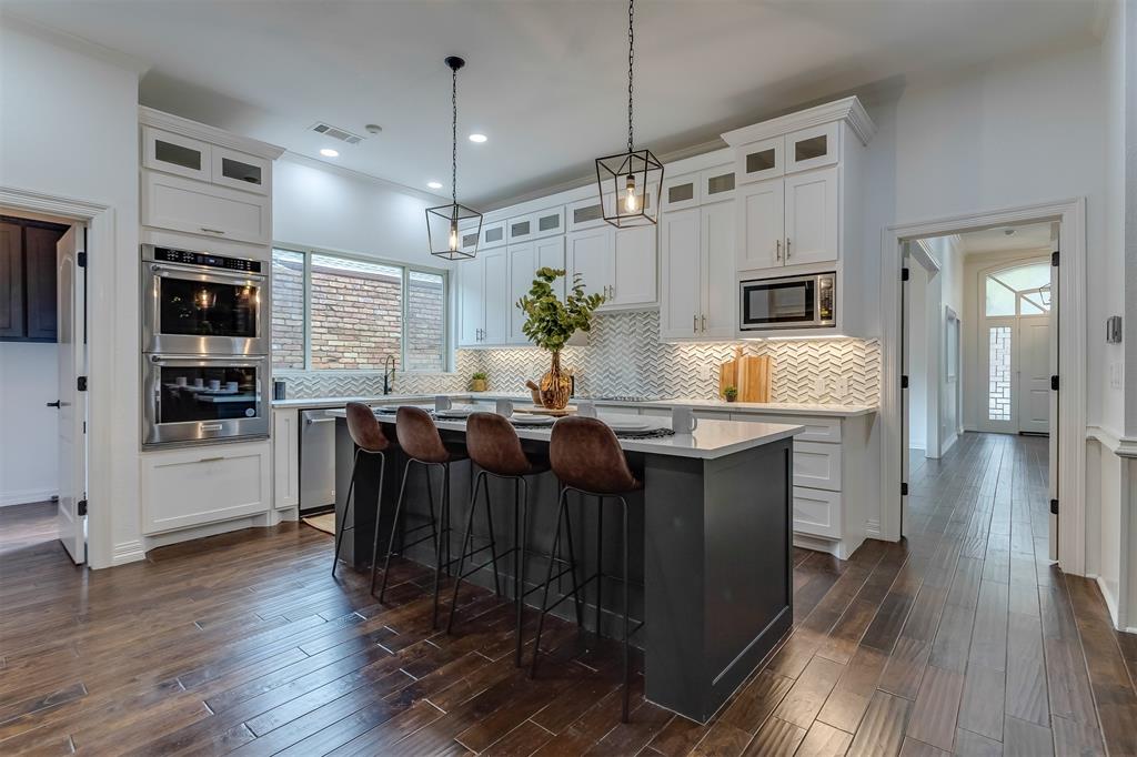 a open kitchen with stainless steel appliances kitchen island granite countertop a refrigerator a stove a sink dishwasher and a dining table with wooden floor