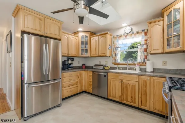 a kitchen with stainless steel appliances granite countertop a refrigerator a sink and white cabinets